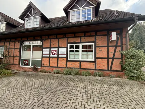 Fachwerkhaus aus rotem Backstein mit Schildern der Kleintierpraxis und Physiotherapie, davor eine gepflasterte Fläche
