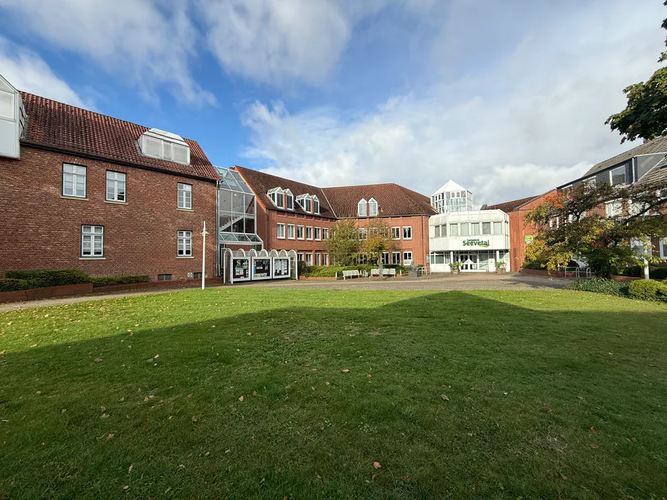 Rasenfläche vor dem Rathauskomplex Seevetal mit Klinkergebäuden, Schaukästen und weißem Eingangsbau im Hintergrund