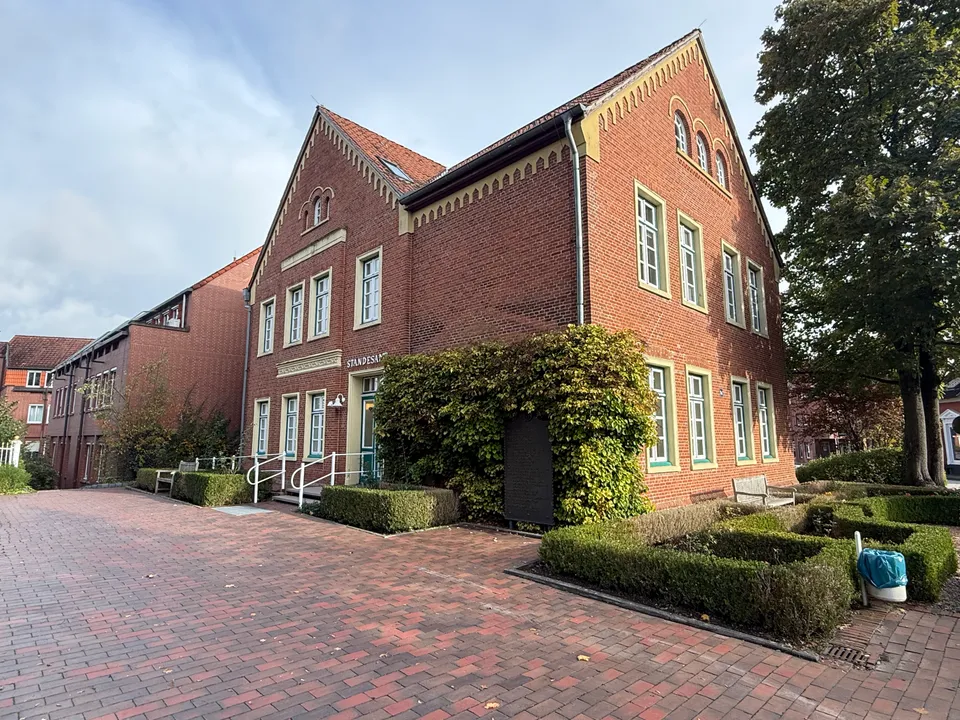 Historisches Backsteingebäude mit zwei Ziergiebeln und Standesamt-Schriftzug, davor gepflasterter Platz, Hecken und großer Baum